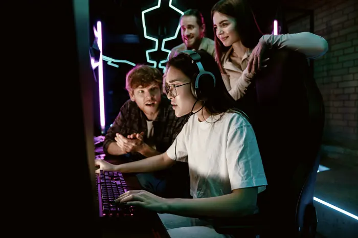 A player at a competitive station mid-match, teammates leaning in behind the chair.