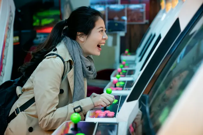 A visitor lit up mid-laugh at a cabinet, hands on the buttons.