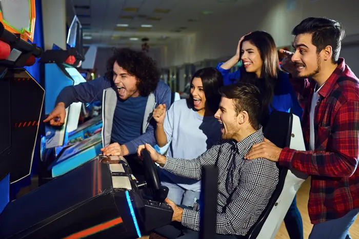 Friends cheering a player on at a cabinet, mid-victory.
