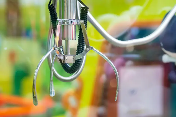 A claw machine grabber in close-up, mid-descent.