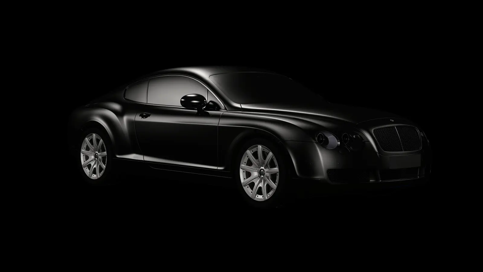 A black grand touring coupé in a black studio, one sweep of light along its body