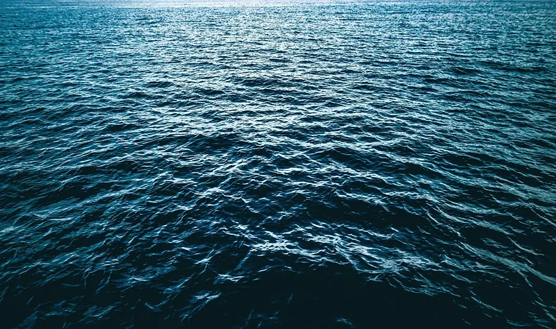 Open sea at dusk: deep blue water rippled to the horizon, the light almost gone.
