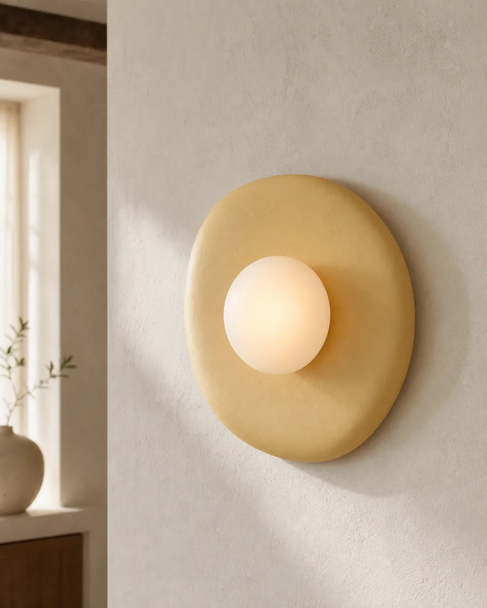 Butter yellow Pebble Sconce on a plaster wall