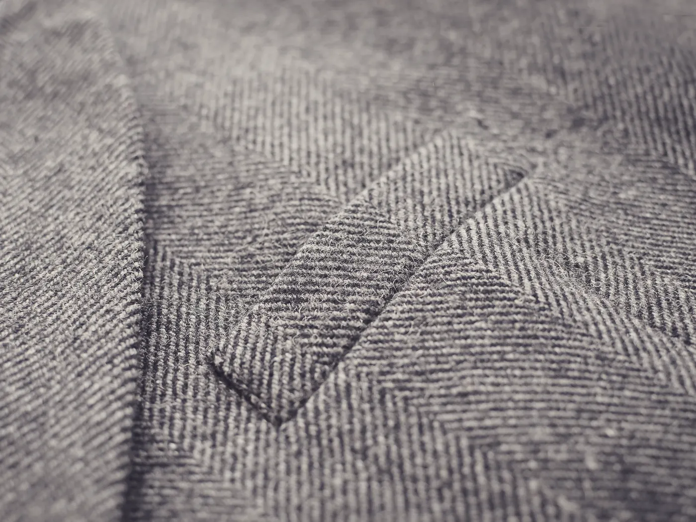 Macro of a grey tweed coat, showing the pocket seam and weave.