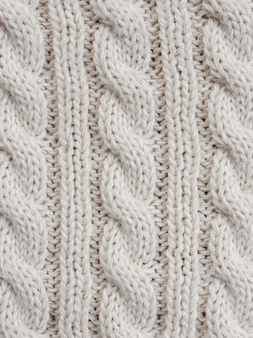 Macro of an ecru cable-knit stitch.