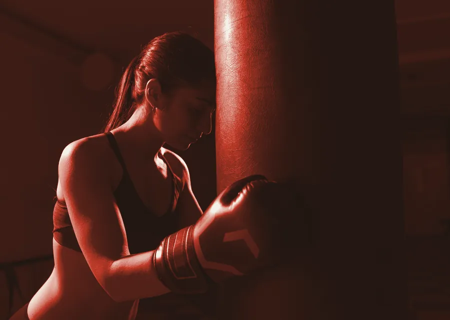 A boxer leans into the heavy bag mid-combination, printed in red duotone.