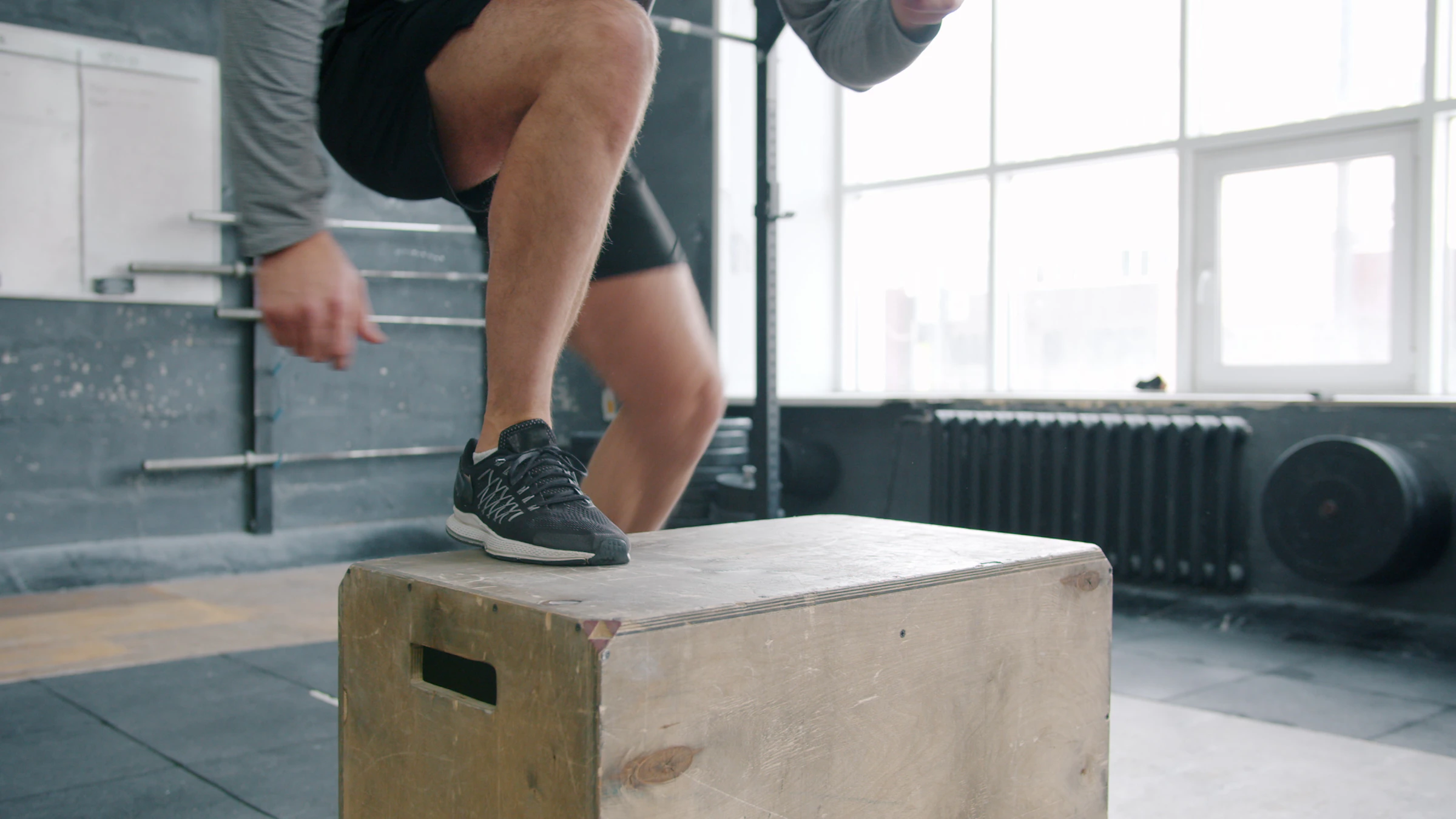 Athlete landing an explosive box jump in a performance gym