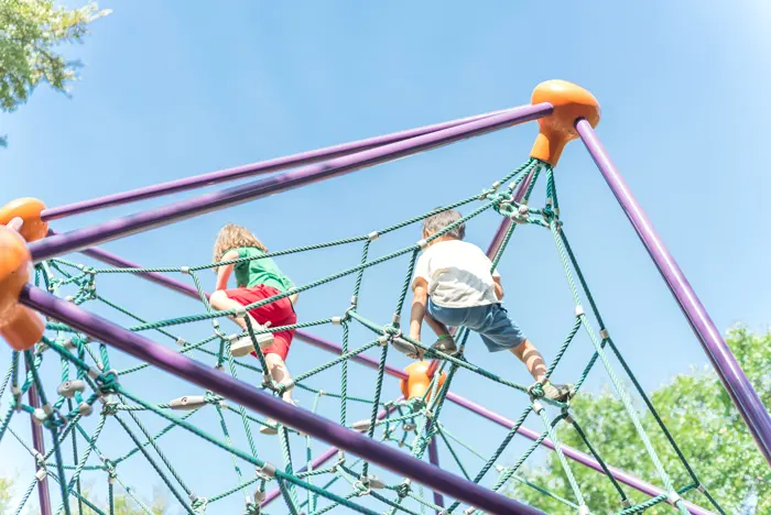 Children on a climbing dome photographed from below against the sky.