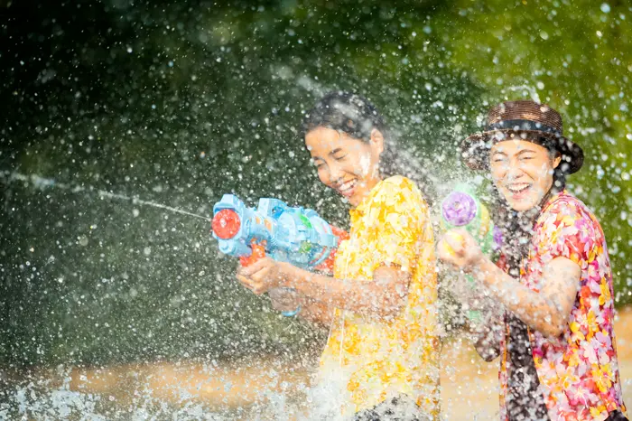 Two visitors mid-water-fight, laughing through the spray.