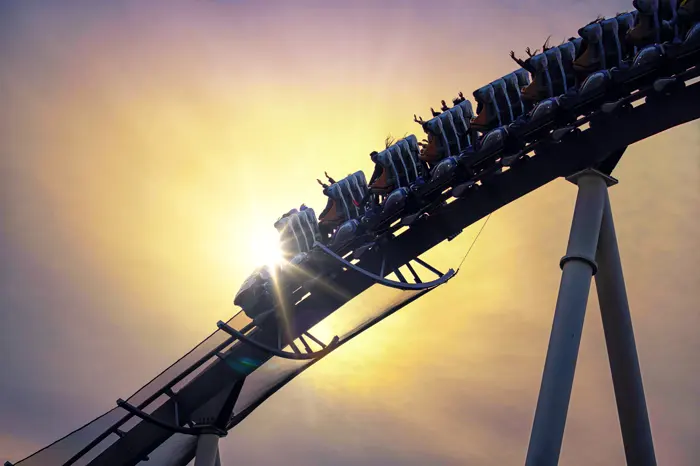 A coaster train cresting a hill in silhouette against the low golden sun.