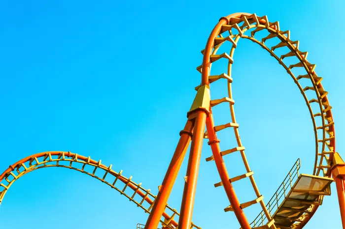 A marigold coaster loop against a clean blue sky.