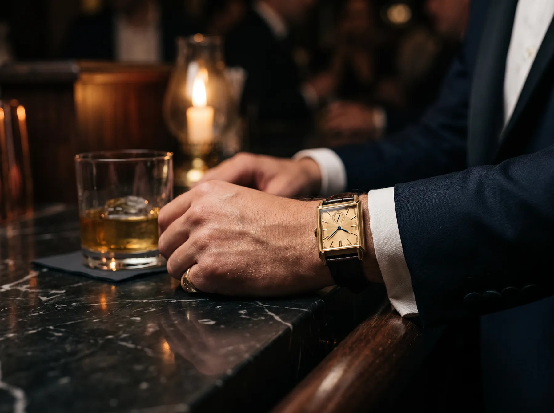 The watch on a wrist beneath a dinner-jacket cuff, resting on a marble bar.